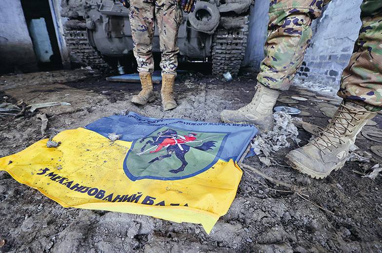 ДМИТРИЙЯГОДКИН/ТАСС Военнослужащие танкового батальона 1-й славянской бригады ДНР около трофейного флага Вооруженных сил Украины